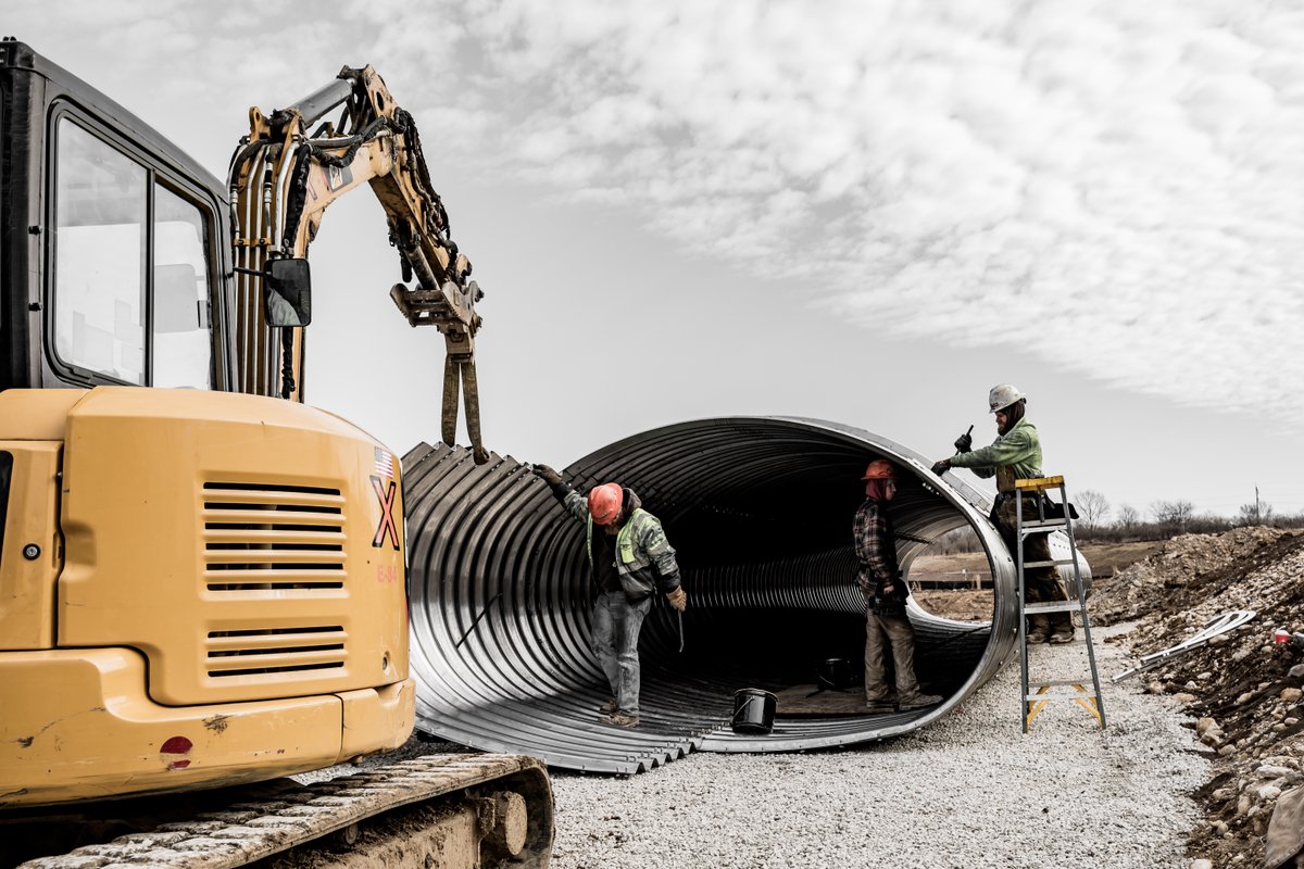 Construction workers in a large metal tube